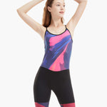 Front view of the Velocity Women’s Unisuit, showing the model with her hands on her head while highlighting the bold swirling abstract design and secure fit.